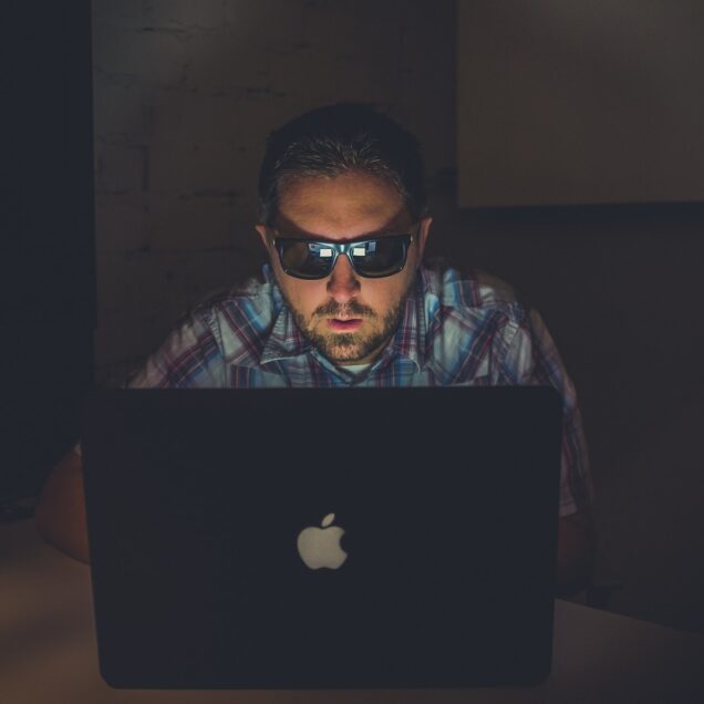man wearing sunglasses using MacBook